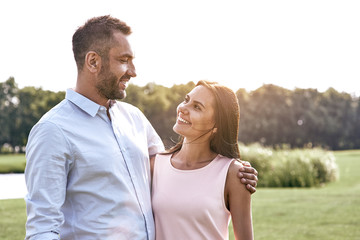 Fototapeta premium Romantic time. Young couple standing in the park hugging looking