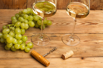 Copas de vino blanco con uvas sobre madera rústica