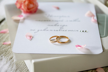 Two Golden Wedding Rings, box of chocolates and a wedding invitation, an inscription that the story of true love never ends, close-up.