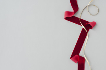 Red velvet ribbon and gold satin ribbon on gray background