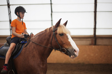 Boy in helmet learning Horseback Riding