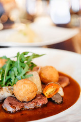 Sirloin beef steak with potato crogettes and arugula salad and gravy
