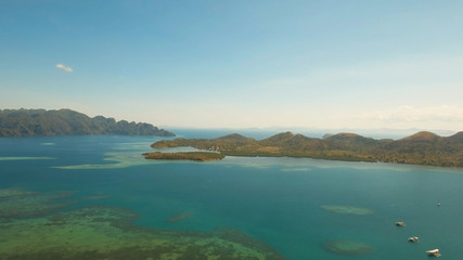 Fototapeta premium Aerial view: beach, tropical island, sea bay and lagoon, mountains with rainforest, Palawan. Lagoon with blue, azure water in the middle of small islands and rocks. Busuanga. Seascape, tropical