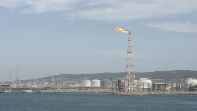 Flare stack of petrochemical refinery on sea shore