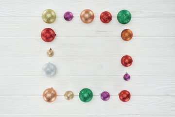 top view of shiny colorful christmas balls on white wooden background