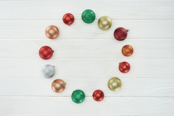 round frame made of beautiful colorful christmas balls on white wooden surface