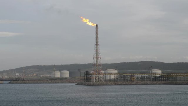 Flare stack of petrochemical refinery on sea shore