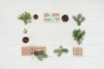 top view of christmas presents, shiny golden balls, pine cones and coniferous twigs on wooden background
