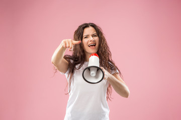 Obraz premium Woman making announcement with megaphone at pink studio. Human facial emotions concept. Trendy colors