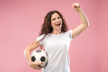 Fan sport woman player holding soccer ball isolated on pink studio background. Human facial emotions concept. Trendy colors