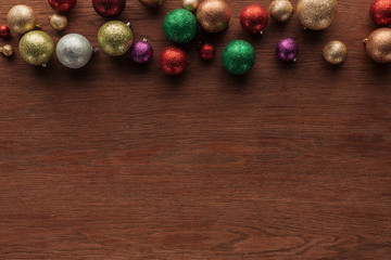 top view of beautiful shiny colorful baubles on wooden surface, christmas background