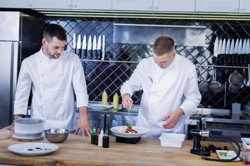 Teamwork. Young talented cooks cooking while working together