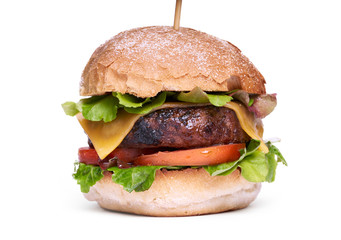 A cheese burger with lettuce, tomatoes and crusty bread bun isolated on a white background.