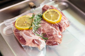 Sous vide steak with rosemary and lemons in vacuumed package.