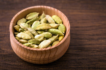 Cardamom, pods in a cup on a wooden background, Indian spice