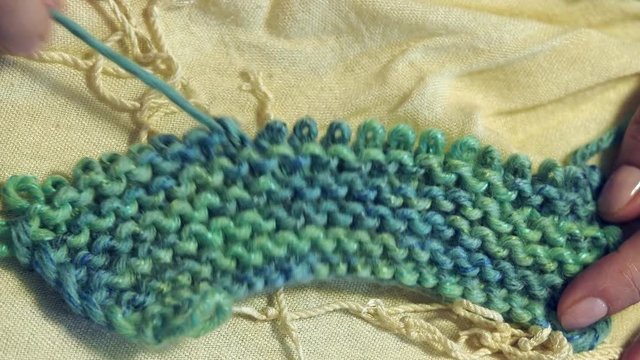 fingers unknit a knitting close up under warm electric light