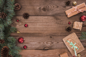 top view of coniferous branches with pine cones, baubles and christmas presents on wooden background