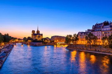 Night view of Cathedral Notre Dame de Paris, island Cite and river Seine in Paris, France
