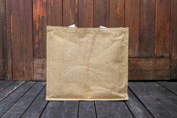Design brown jute grocery bag on wooden floor, outdoor day light, ecological concept object