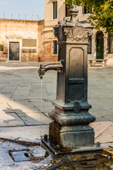 Ancient water fountain in Sotoportego de Ghetto, the Jewish Ghetto, Venice, Italy.