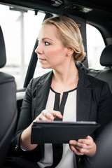 Portrait of young businesswoman travelling in car holding digital tablet