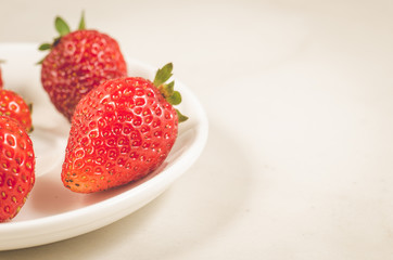 fresh strawberry berries in a white bowl/fresh strawberry berries in a bowl on a white table.  Copy space