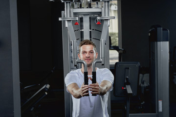 Fototapeta na wymiar Athletic man performing crossover exercise for chest muscles at gym.