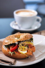 Morning meal, bagel burger with fresh salad and coffee. Gourmet conception.