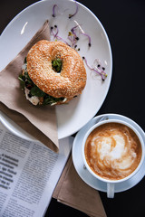 Morning meal, bagel burger with fresh salad and coffee. Top view shot. Gourmet conception.