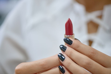 Closeup of red lipstick in hands of woman in store
