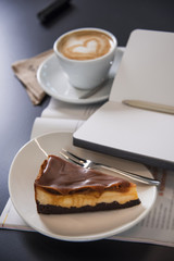 Caramel cheesecake with cappuccino and magazines. Morning meal. 