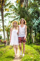 Young honeymoon couple walking among rice fields. Beautiful trip of newleds to Bali island, Indonesia. Nature, summer, green, bright.