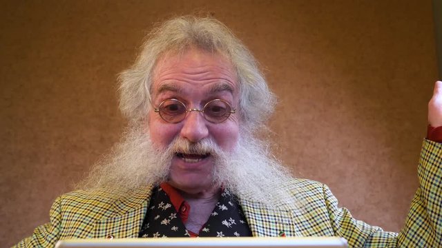 Older man with beard talking to someone through device