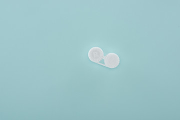 top view of white contact lenses container on blue background