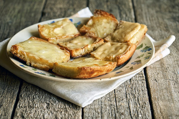 Toasts with melted cheese in an old plate on wooden boards