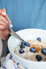 Healthy breakfast oatmeal with banana, blueberries, honey and pine nuts