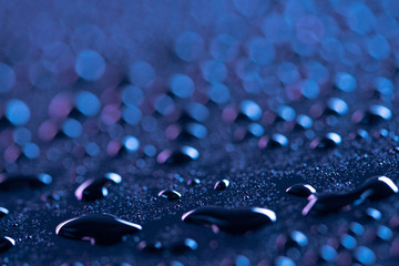 close up view of water drops on blue surface as background