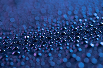 close up view of water drops on blue surface as background