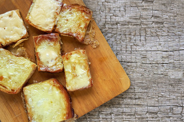 Toasts with melted cheese on a cutting board on wooden boards