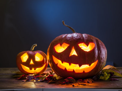 Grinning pumpkin lantern or jack-o'-lantern is one of the symbols of Halloween. Halloween attribute. Wooden background.