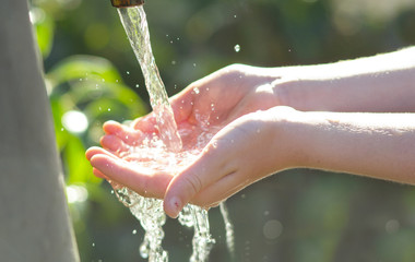 mani di bambina che raccolgono acqua di fonte