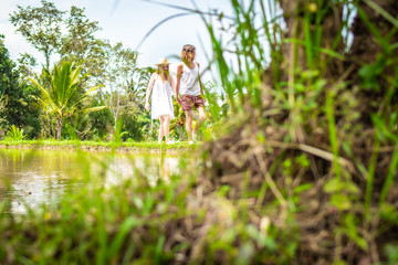 Young honeymoon couple walking among rice fields. Beautiful trip of newleds to Bali island, Indonesia. Nature, summer, green, bright.