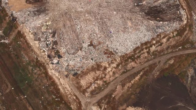City dump or big garbage dump with trucks and bulldozers, aerial view, flight on drone above