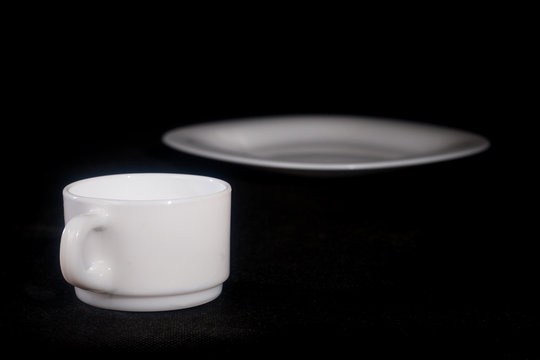 White plate with a mug on a black background