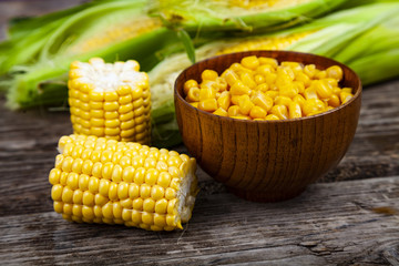Ripe yellow corn and canned corn in a wooden bowl