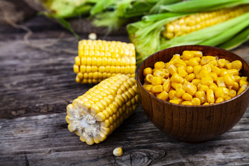 Ripe yellow corn and canned corn in a wooden bowl