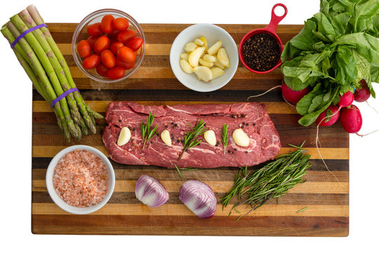 Overhead view of seasoned meat next to vegetables