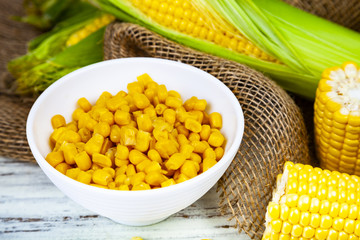 Ripe yellow corn and canned corn in a wooden bowl