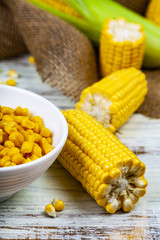 Ripe yellow corn and canned corn in a wooden bowl
