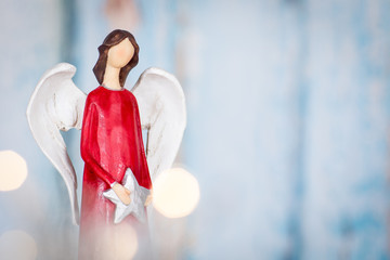 Christmas background with red angel holding a star on blue background with lights